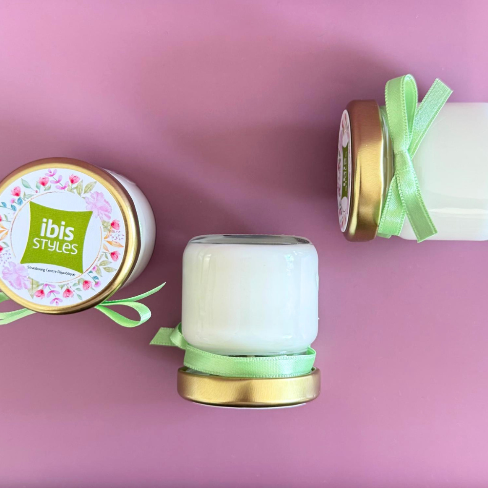 Vue de dessus de bougies personnalisées avec logo d'entreprise, couvercle doré personnalisé et ruban satin vert.
