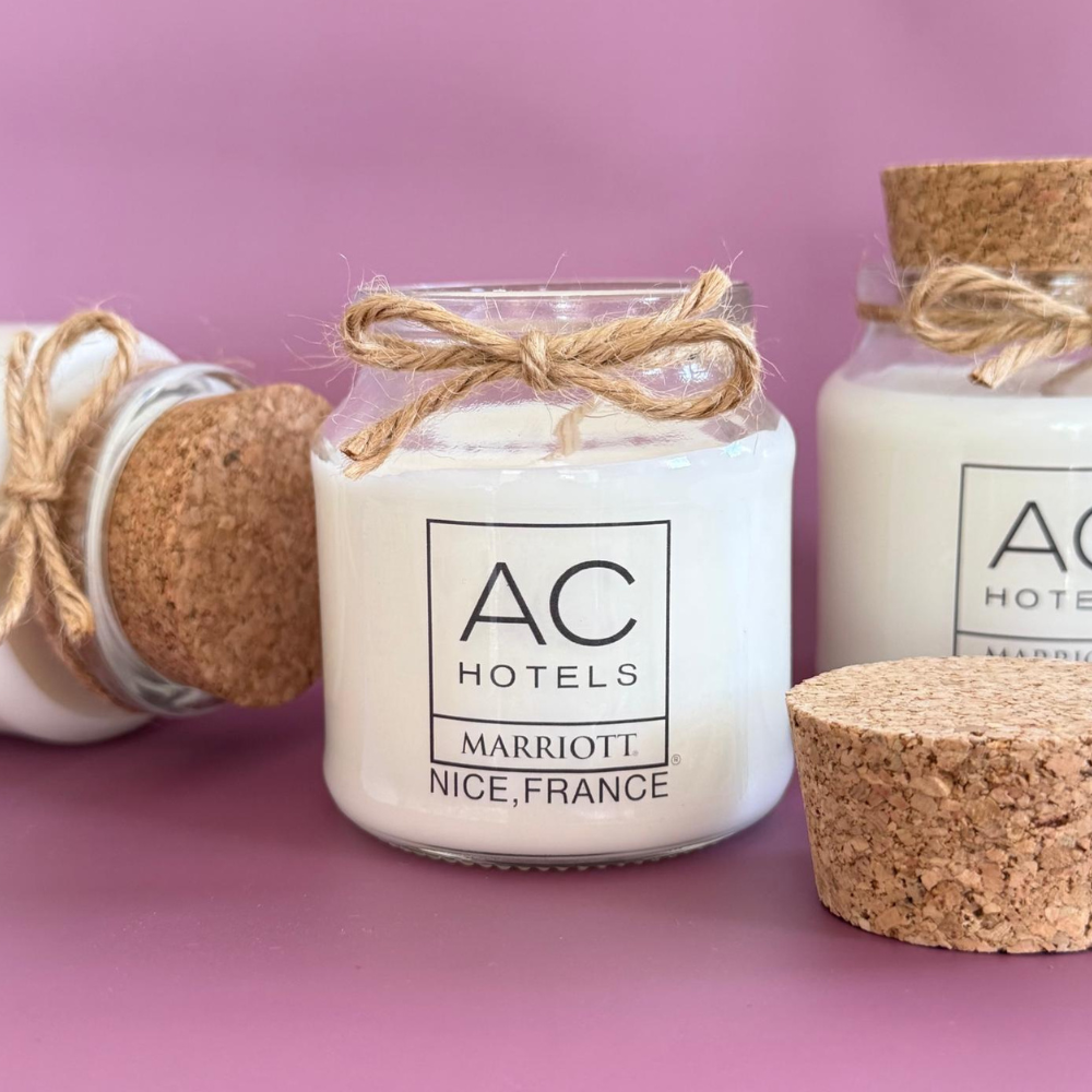Bougie personnalisée avec logo d'hôtel dans un pot en verre transparent, idéale comme cadeau client et goodie d'entreprise.